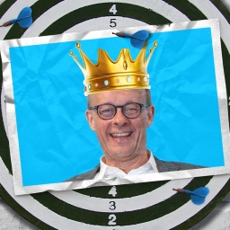 Eine Fotomontage zeigt eine Postkarte auf einer Dartscheibe. Die Postkarte zeigt Friedrich Merz mit einer Krone, aus der ein Zacken herausgebrochen ist.