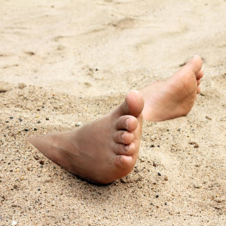 Kinderfüße im Sand am Strand