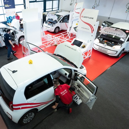 Teilnehmer der Weltmeisterschaft der Kfz-Mechatroniker arbeiten im Haus des KfZ-Gewerbes an einem Elektroauto.