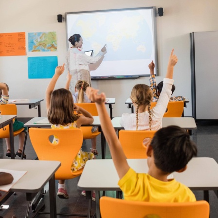 Eine Lehrerin steht vor einer Klasse an einem Whiteboard