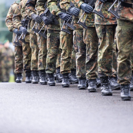 Soldaten marschieren mit Gewehr in Reih und Glied
