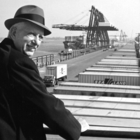 Malcom McLean steht 1957 an einer Reling und blickt auf Containter (Archivbild)