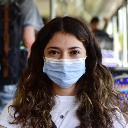 Eine Schülerin trägt beim Busfahren eine Maske