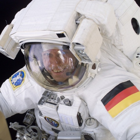 Der Raumfahrer Thomas Reiter bei einem Außeneinsatz im Raumanzug, lächelnd