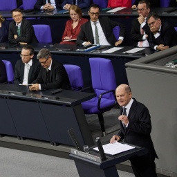 Bundeskanzler Olaf Scholz (SPD) spricht im Bundestag und stellt die Vertrauensfrage. Dahinter die Regierungsbank mit Politikerinnen und Politikern von SPD und Grünen.