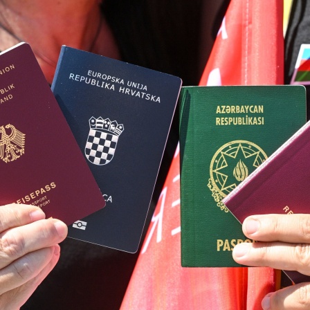 Menschen zeigen bei einem Fototermin zur Unterstützung des neuen Staatsangehörigkeitsrecht die beiden Pässe, den deutschen und den kroatischen und aserbaidschanischen. Wer sich Einbürgern lassen will, darf seine bisherige Staatsbürgerschaft behalten. Das Gesetz zur Modernisierung des Staatsangehörigkeitsrechts tritt am 27. Juni 2024 in Kraft.