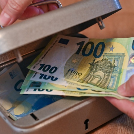 Eine Frau holt vier Einhundert-Euro-Scheine aus einer kleinen Geldkassette