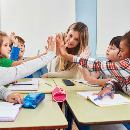 Kinder einer Schulklasse klatschen ihre Hände zusammen