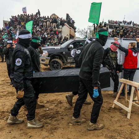 Vermummte Mitglieder der Terrororganisation Hamas tragen einen Sarg mit den sterblichen Überresten einer Geisel zur Übergabe an das Internationale Rote Kreuz (IKRK) in Chan Junis im südlichen Gazastreifen.