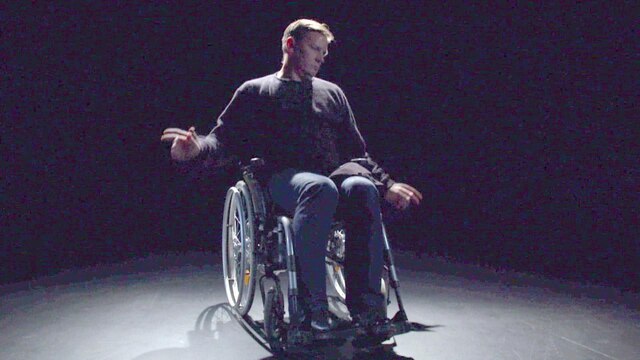 Ein Mann im Rollstuhl steht im Rampenlicht eines Studios