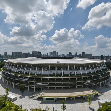 Fotografie des neu gebaute Japan National Stadiummit der Stadtsilhouette von Tokio im Hintergrund. 