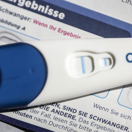 Ein positiver Schwangerschaftstest liegt auf einem Beipackzettel