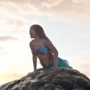Eine Meerjungfrau (Halle Bailey) sitzt auf einem Felsen im Musical "Arielle die Meerjungfrau, eine Realverfilmung 