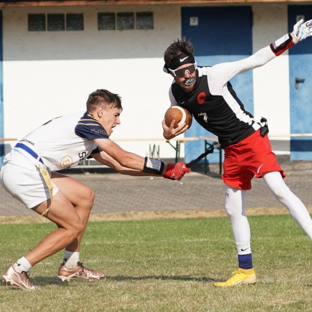Beim Flag Football versucht ein Abwehrspieler, einem Angreifer eine Flagge aus dem Gürtel zu ziehen