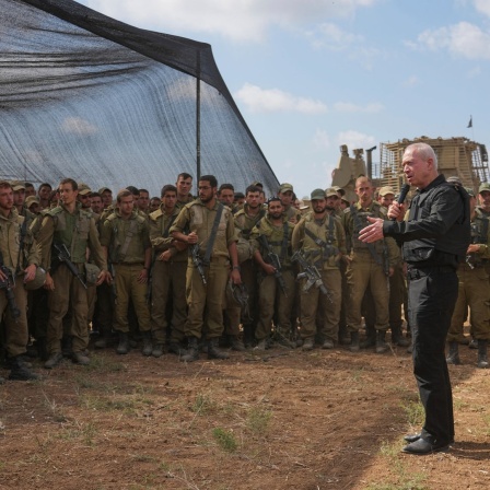 Yoav Gallant (M), Verteidigungsminister von Israel, der eine Schutzweste trägt, spricht mit israelischen Soldaten nahe der Grenze zum Gazastreifen.