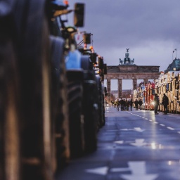 Traktoren und LKWs blockieren die Straße des 17. Juni, im Hintergrund ist das Brandenburger Tor zu sehen.