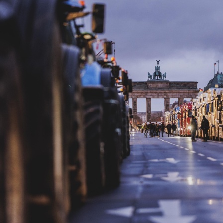 Traktoren und LKWs blockieren die Straße des 17. Juni, im Hintergrund ist das Brandenburger Tor zu sehen.