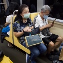 Fahrgäste in der U-Bahn von Taipeh. Die meisten tragen Masken und schauen auf ihre Smartphones.
