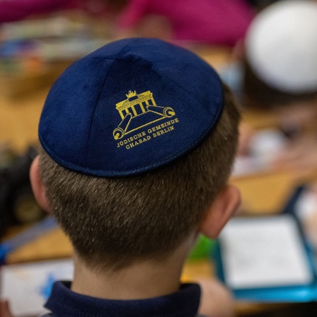 Ein ukrainischer Junge mit einer Kippa auf dem Kopf sitzt zusammen mit anderen Kindern an einem Tisch im jüdischen Flüchtlingsheim. © dpa/Monika Skolimowska