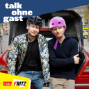 Die Hosts von "Talk ohne Gast", Till Reiners und Moritz Neumeier sitzen mit Fahrradhelmen auf dem geöffneten Kofferraum eines roten Autos. (Quelle: Fritz)