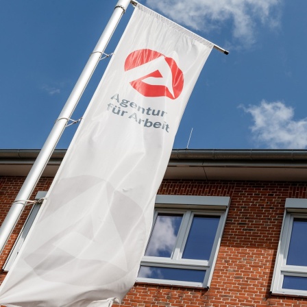 Vor der Agentur für Arbeit in Lüneburg weht eine Fahne.