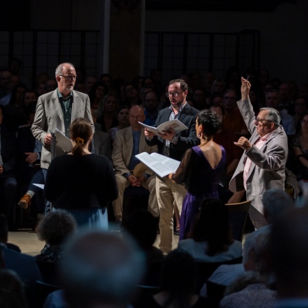 Das Huelgas Ensemble und Paul Van Nevel stehen in einem Kreis