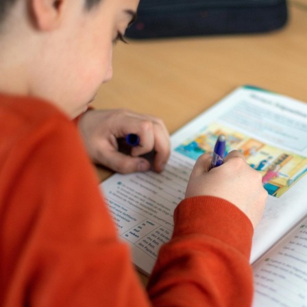  Ein Schüler schreibt während des Unterrichts in einer Grundschule in einem Schulbuch. 