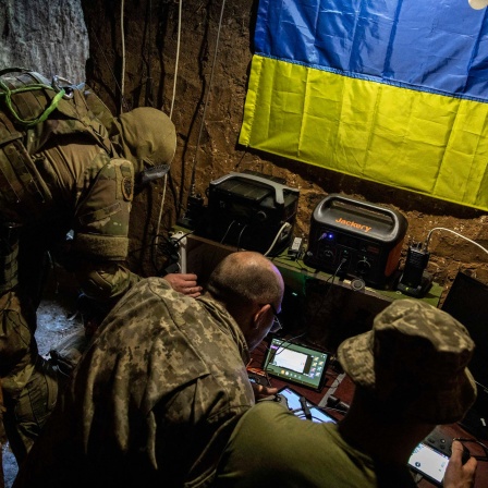 Ukrainische Soldaten sitzen vor Displays und steuern einen Drohnen-Einsatz. 