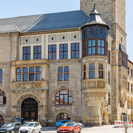 Blick auf das Rathaus in Dessau-Roßlau, im Vordergrund parken Autos. 