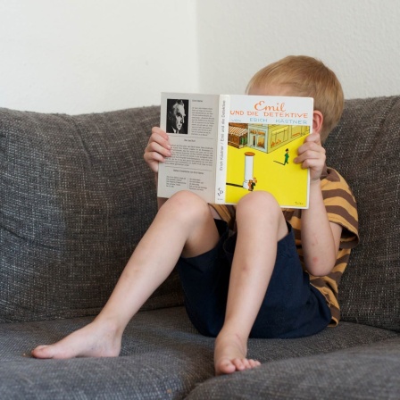 Ein Junge liest am 17. Juli in einem Buch von Erich Kästner. Das Buch Emil und die Detektive haben schon viele gelesen. 
