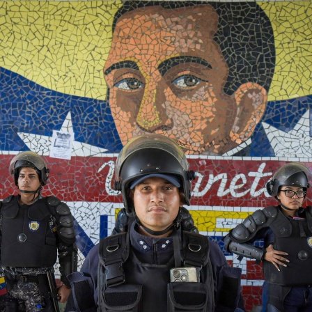 Mitglieder der venezolanischen Polizei patrouillieren am 31. Juli in der venezolanischen Hauptstadt Caracas vor einem Wandbild des Nationalhelden Simón Bolívar.