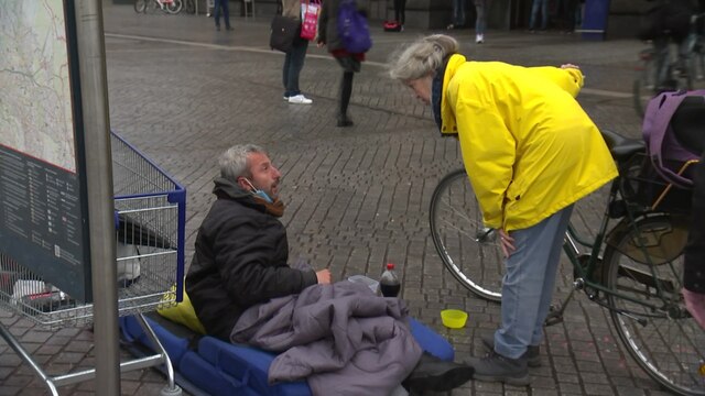 Eine Frau im Pensionsalter kümmert sich um einen Obdachlosen.