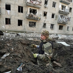 Nach einem russischen Angriff auf die ukrainische Stadt Charkiw inspizieren Polizeibeamte einen Krater vor einem beschädigten Wohnhaus, das getroffen wurde.