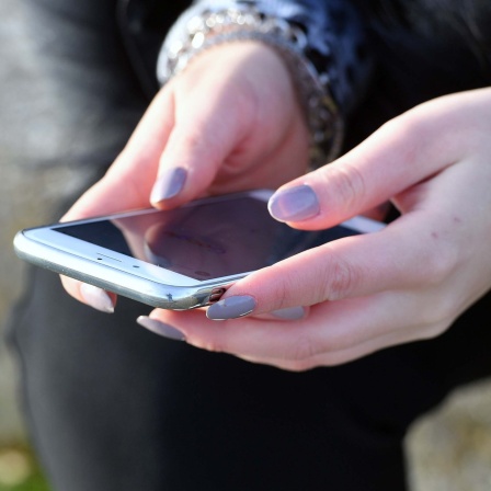 Ein Mensch schaut auf sein Smartphone.