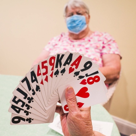 Damen spielen mit Maske Karten