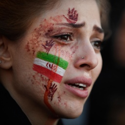 Eine junge Frau mit der von Tränen verschmierten iranischen Flagge und roten Händen auf ihrem Gesicht. Auf einer Demonstration wegen des Todes von Mahsa Amini im Iran. Paris, 9.Oktober 2022. 