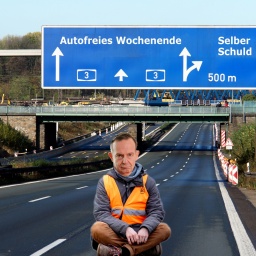 Volker Wissing sitzt in Blockade-Haltung auf einer leeren Autobahn