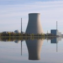 Der Kühlturm des stillgelegten Kernkraftwerks Isar II spiegelt sich im Wasser. Es steigt kein Dampf daraus auf.