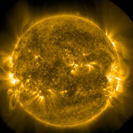 Eine Aufnahme der Sonne, auf Strahlungen und Verwirbelungen kenntlich sind. Es ist ein gelbliche Aufnahme.