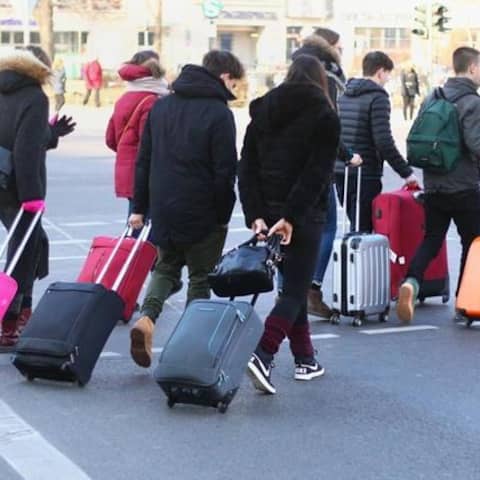 Junge Touristen ziehen ihre Rollkoffer über eine Straße