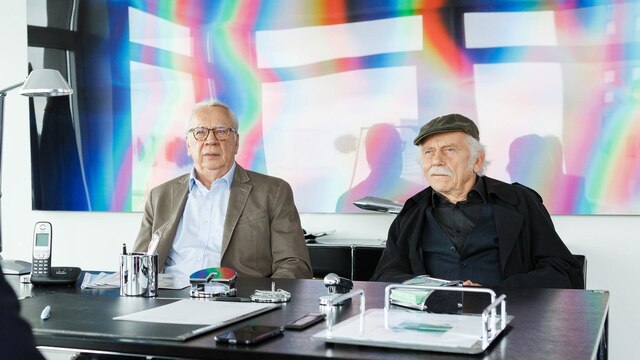 Peter Lerchenbaumer und Tilo Brückner sitzen vor Schreibtisch.