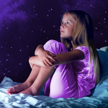 Mädchen im Bett vor Sternenhimmel mit Erdkugel