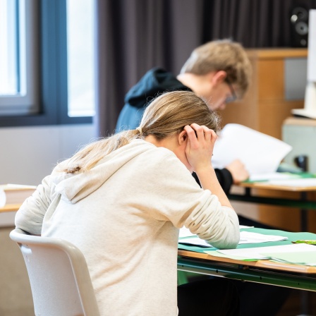 Schüler sitzen im Klassenzimmer und schreiben eine Abiturprüfung