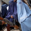 Ein Taliban-Kämpfer hält sein Gewehr in der Hand, während Menschen in Kabul auf die Verteilung von Lebensmittelrationen durch eine südkoreanische Hilfsorganisation warten.