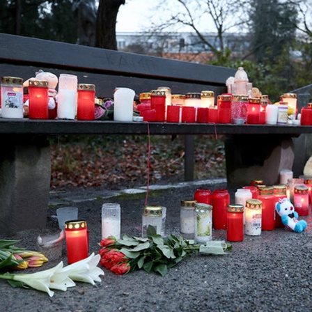 rauerkerzen, Blumen und Kuscheltiere liegen nach dem tödlichen Angriff in einem Park am Tatort auf einer Bank. In einem Park in Aschaffenburg waren am Vortag ein zweijähriger Junge und ein 41-jähriger Mann getötet sowie weitere Menschen schwer verletzt worden.