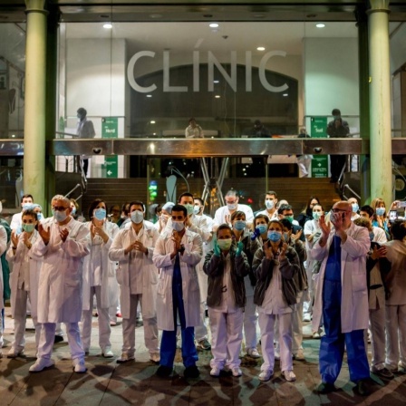 Pflegekräfte stehen am 25. März vor einem Krankenhaus in Barcelona und applaudieren.