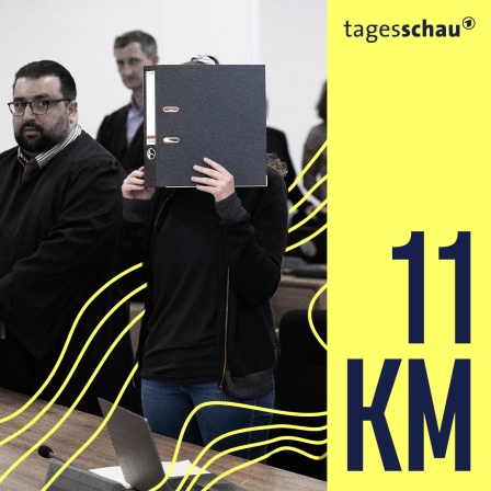 Die Angeklagte Lina E. (M) steht bei der Fortsetzung des Prozesses im Oberlandesgericht (OLG) Dresden im Verhandlungssaal und hält einen Aktenordner vor ihr Gesicht.