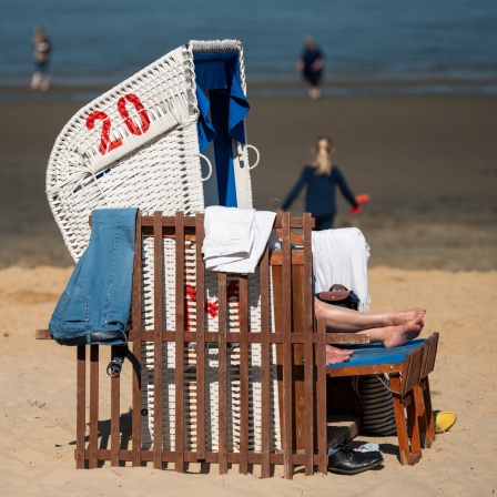 Menschen und ein Strandkorb am Strand von Cuxhaven bei sonnigen Wetter