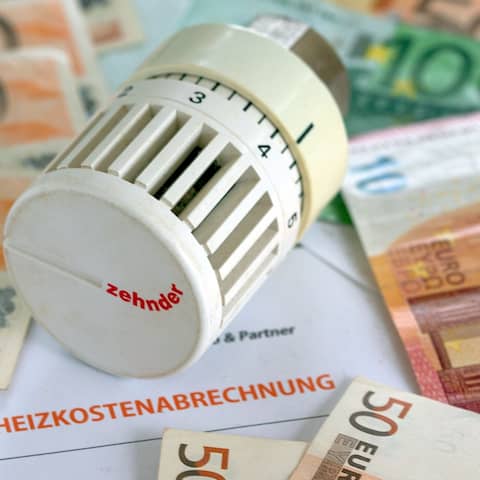 ILLUSTRATION - Ein Heizungsthermostat liegt auf der Heizkostenabrechnung und Euro-Geldscheinen.