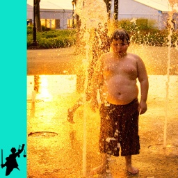 Ein junges Mädchen und ein Junge spielen mit Wasserfontänen im Battery Park in New York City bei Sonnenuntergang.